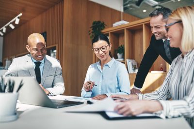 Group of accountants crowded round a table working on budgets together.