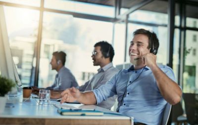 Row of male IT support desk workers chatting on their headsets.